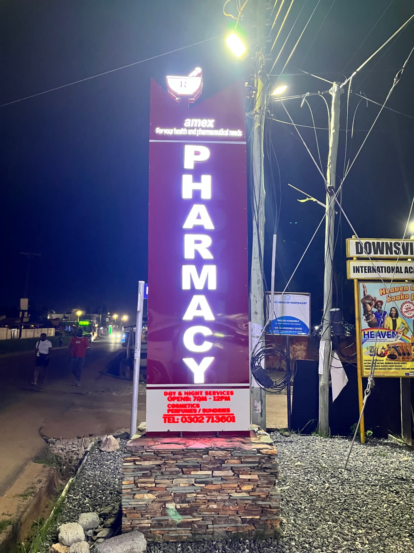 Illuminated Amex Pharmacy signage at the Accra branch at night